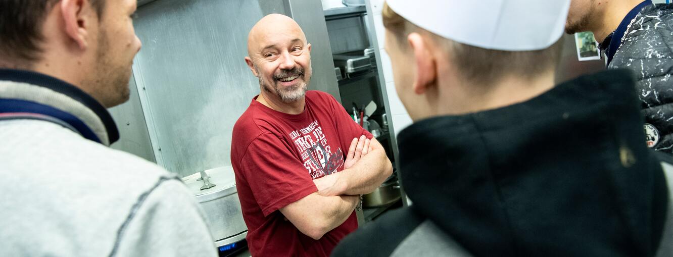 Un formateur en cuisine avec trois apprentis